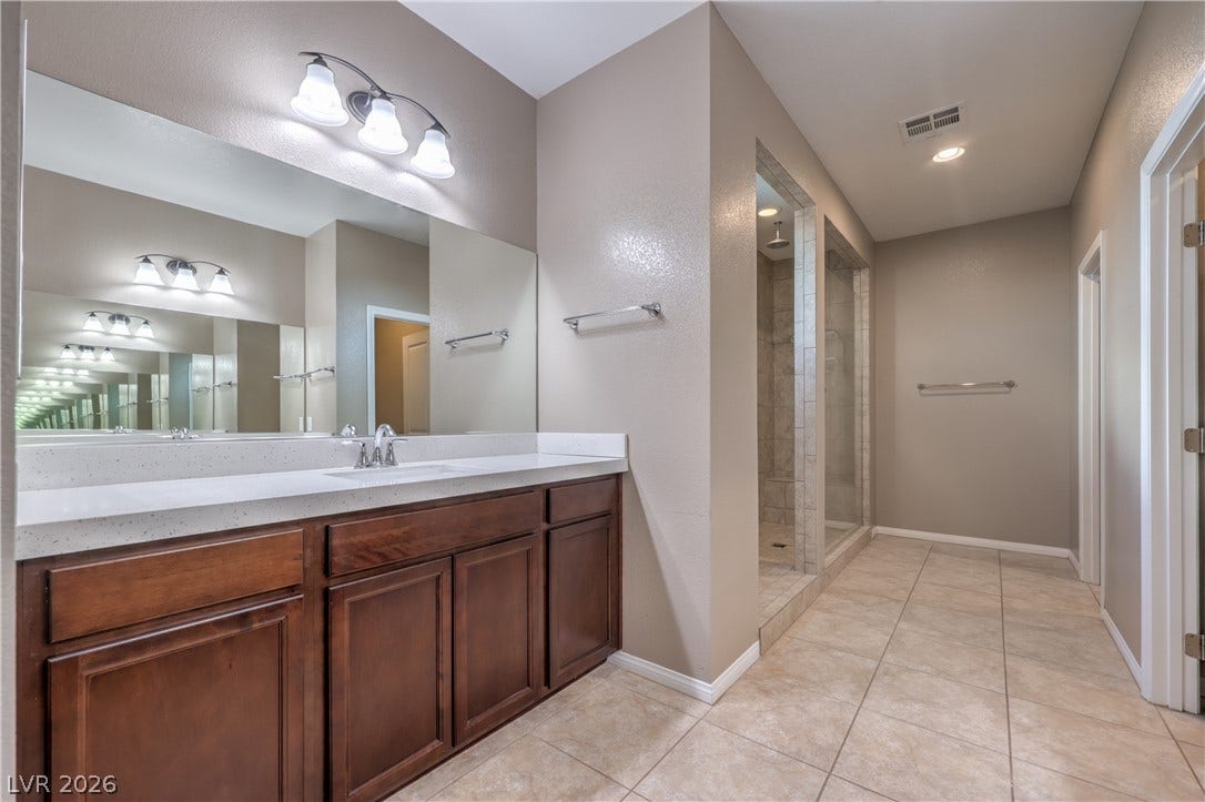 4658 Chestnut Tiger Street, North Las Vegas, NV 89031 Clean lines and warm wood cabinetry define this spacious bathroom featuring a tiled walk-in shower.