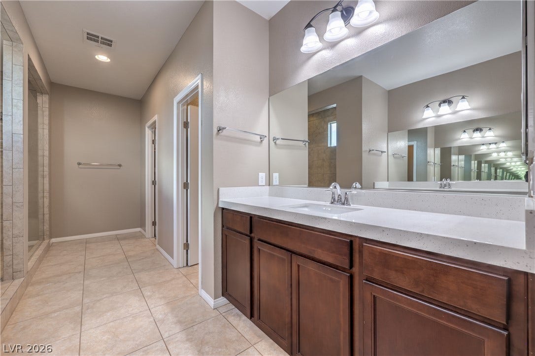 4658 Chestnut Tiger Street, North Las Vegas, NV 89031 Ample counter space and a large mirror define this bathroom, complemented by tile flooring.