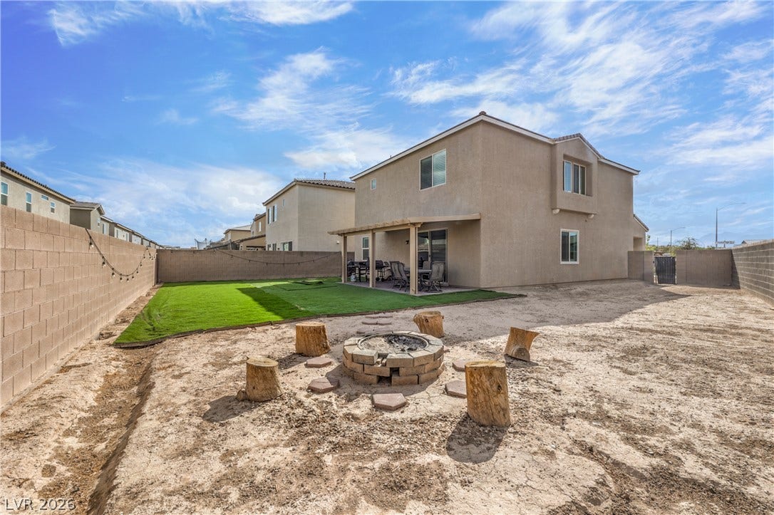 4658 Chestnut Tiger Street, North Las Vegas, NV 89031 A spacious backyard features a stone fire pit alongside a green lawn and covered patio.