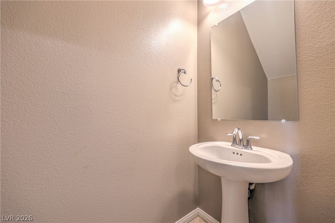 4658 Chestnut Tiger Street, North Las Vegas, NV 89031 A classic pedestal sink pairs with a frameless mirror in this powder room.