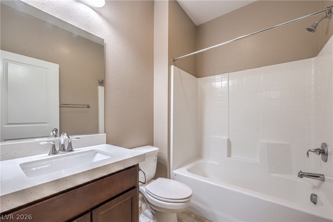 4658 Chestnut Tiger Street, North Las Vegas, NV 89031 An undermount sink and stone counter vanity stand beside a tiled shower tub combination.