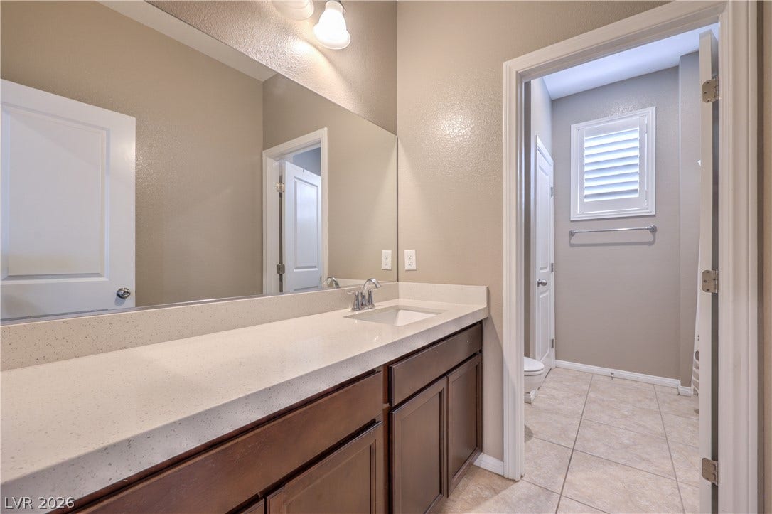 4658 Chestnut Tiger Street, North Las Vegas, NV 89031 Smooth stone countertops and rich wooden cabinetry anchor this clean bathroom design.