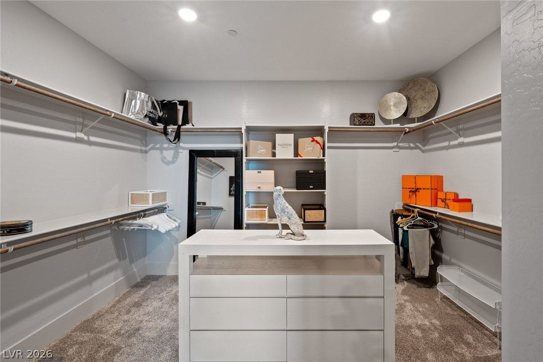 A spacious walk-in closet includes recessed lighting and extensive built-in shelving.