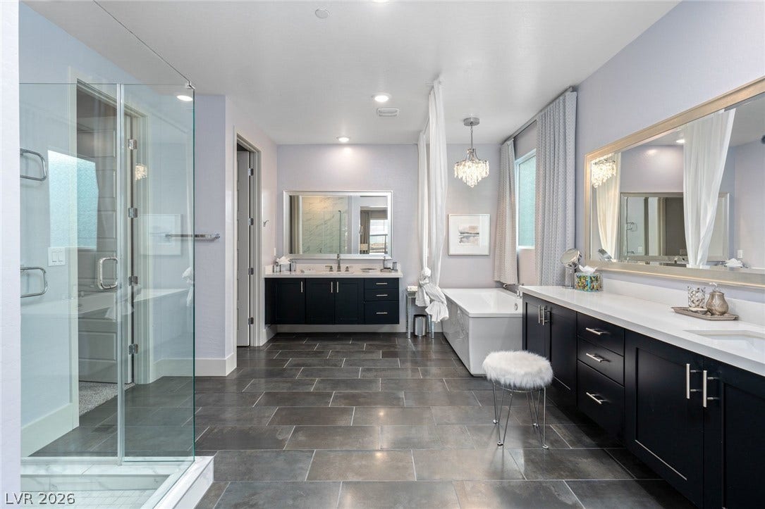 Gleaming tile floors anchor this well-appointed bathroom complete with dual vanities and a soaking tub.