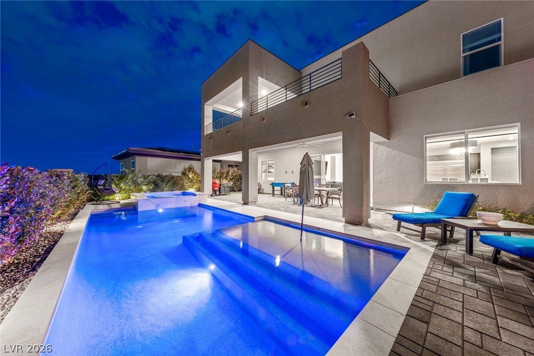 An inviting backyard oasis features a modern swimming pool bordered by brick pavers.