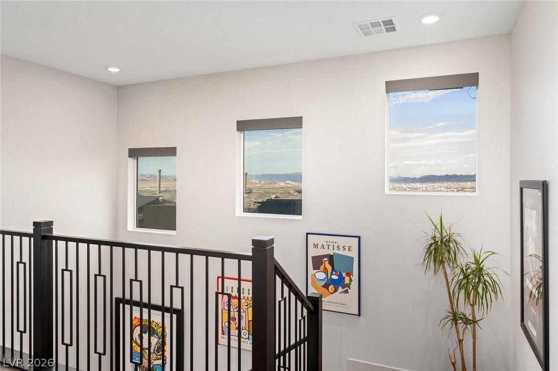 Three vertical windows frame distant mountain views from the upper stair landing.