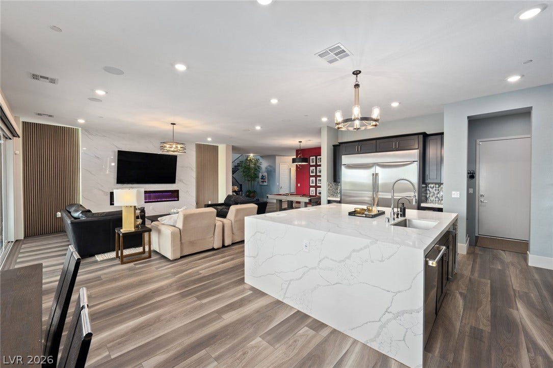 An open floorplan seamlessly connects the contemporary kitchen and living areas over stylish wood flooring.