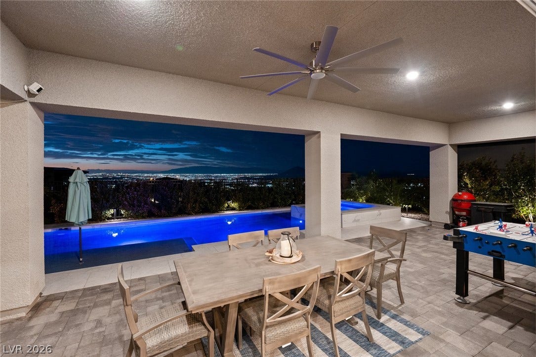 Panoramic city views frame the covered patio overlooking a gleaming pool and spa.