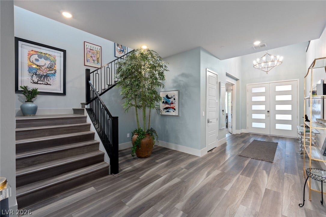 A spacious double-door entry foyer reveals wood-look flooring and an elegant staircase.