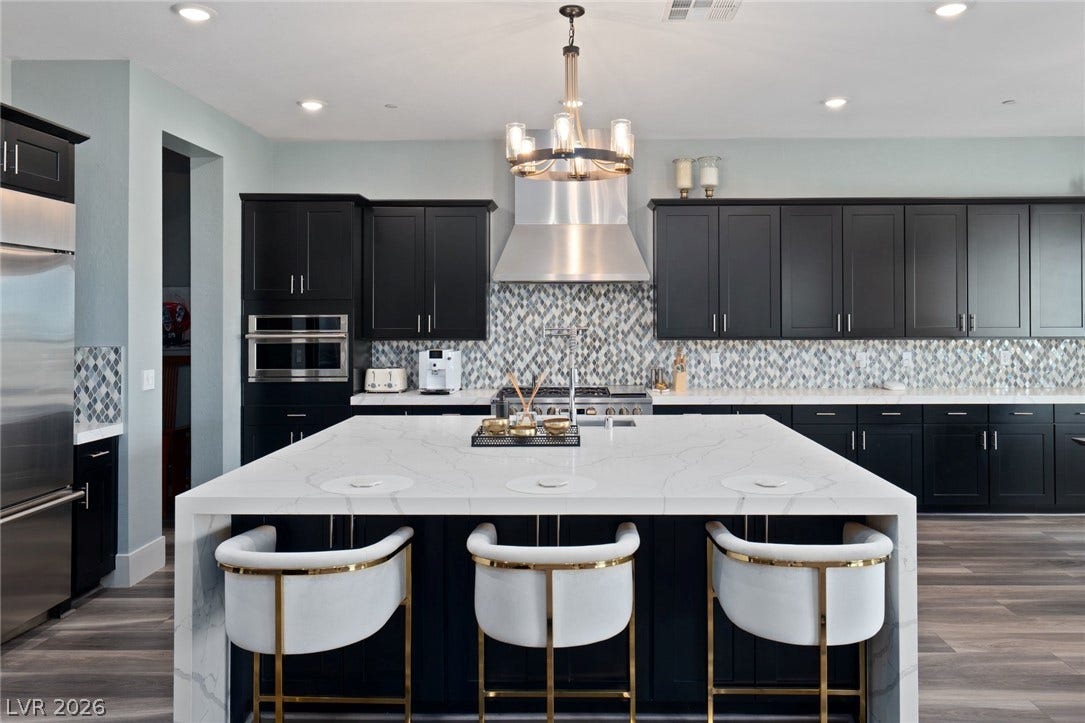 Dark cabinetry and veined stone countertops anchor this modern culinary workspace with wood flooring.