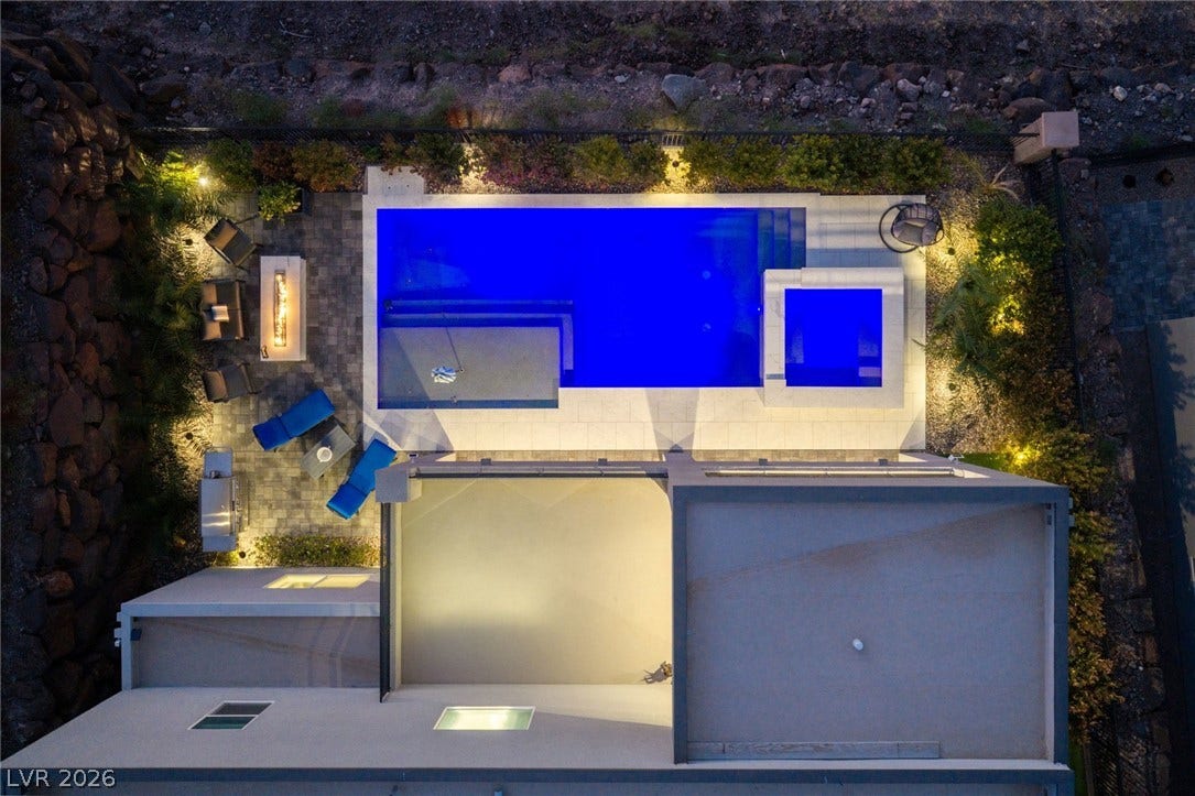 An aerial perspective reveals a sleek swimming pool, adjoining spa, and paved lounge terrace.