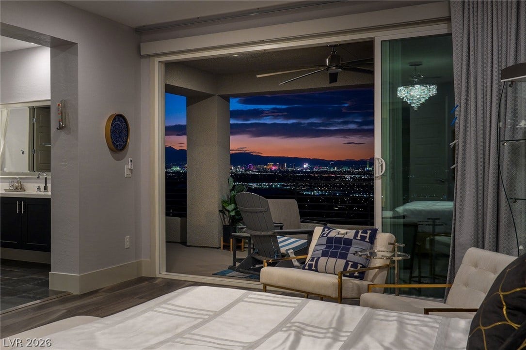 Sliding glass doors frame a spectacular city lights panorama from the bedroom.