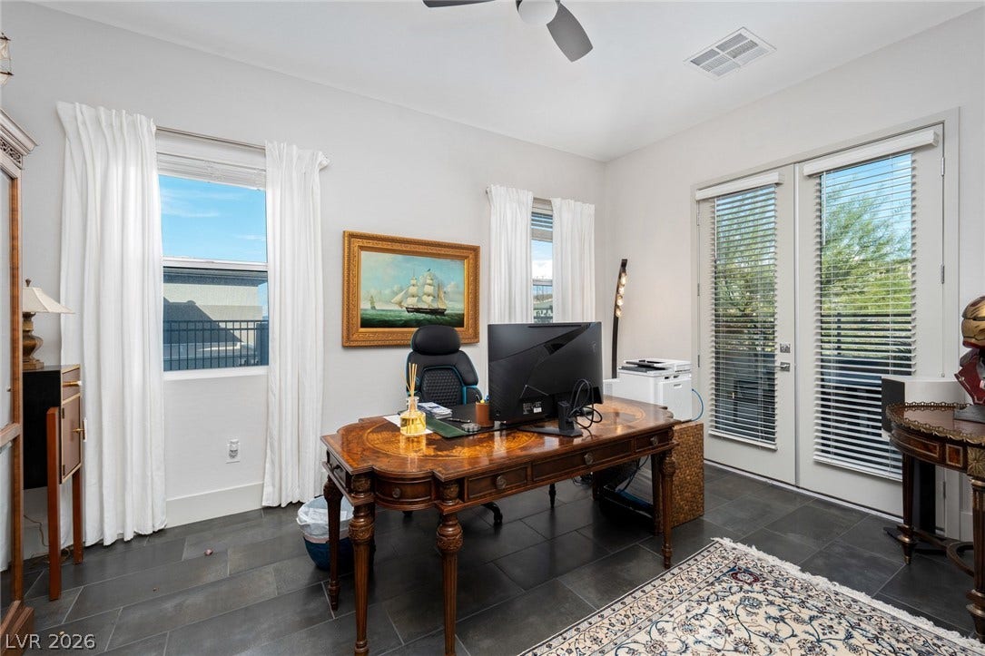 Dark stone tile flooring and glass double doors define this versatile workspace.