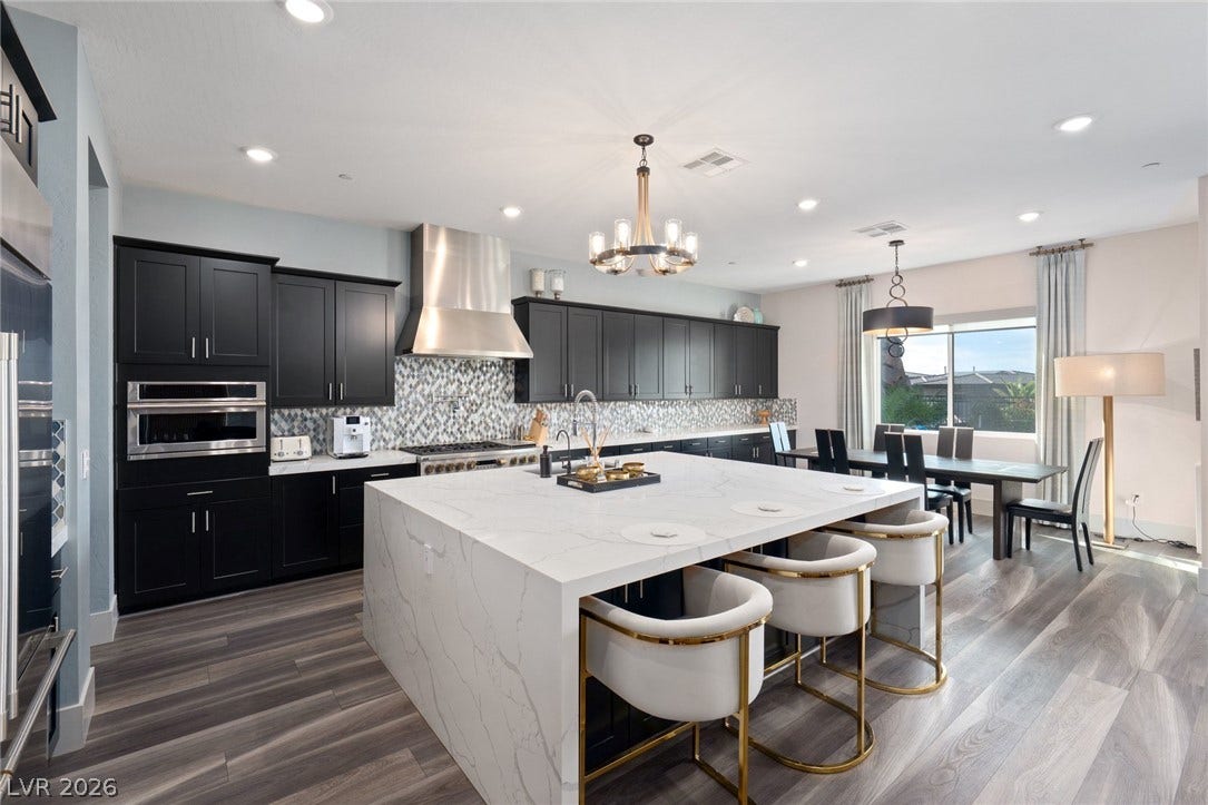 Sophisticated dark cabinetry contrasts with a waterfall-edge stone island and modern wide-plank flooring.