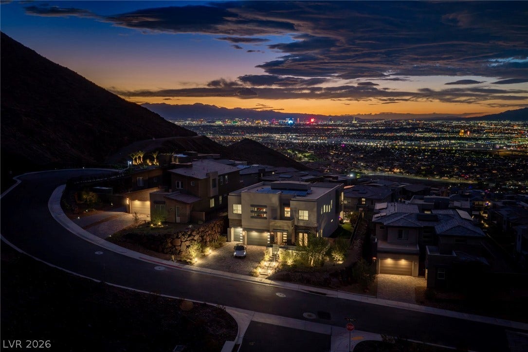 Dramatic hillside architecture commands glittering city lights and mountain horizons at twilight.