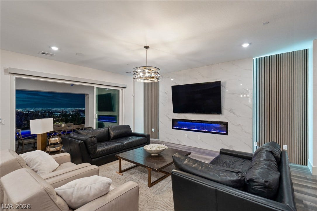 Sliding glass doors frame far-reaching city lights from the open living area.