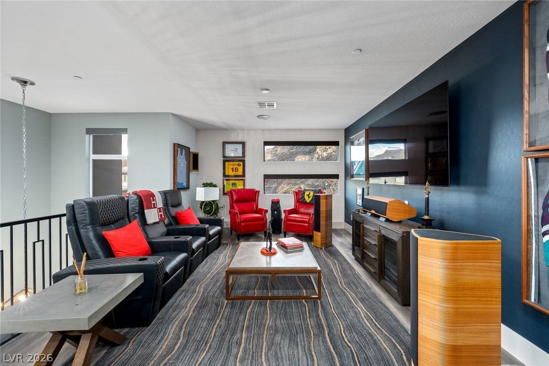 A spacious upper-level loft features a modern media setup and views of the surrounding hills.