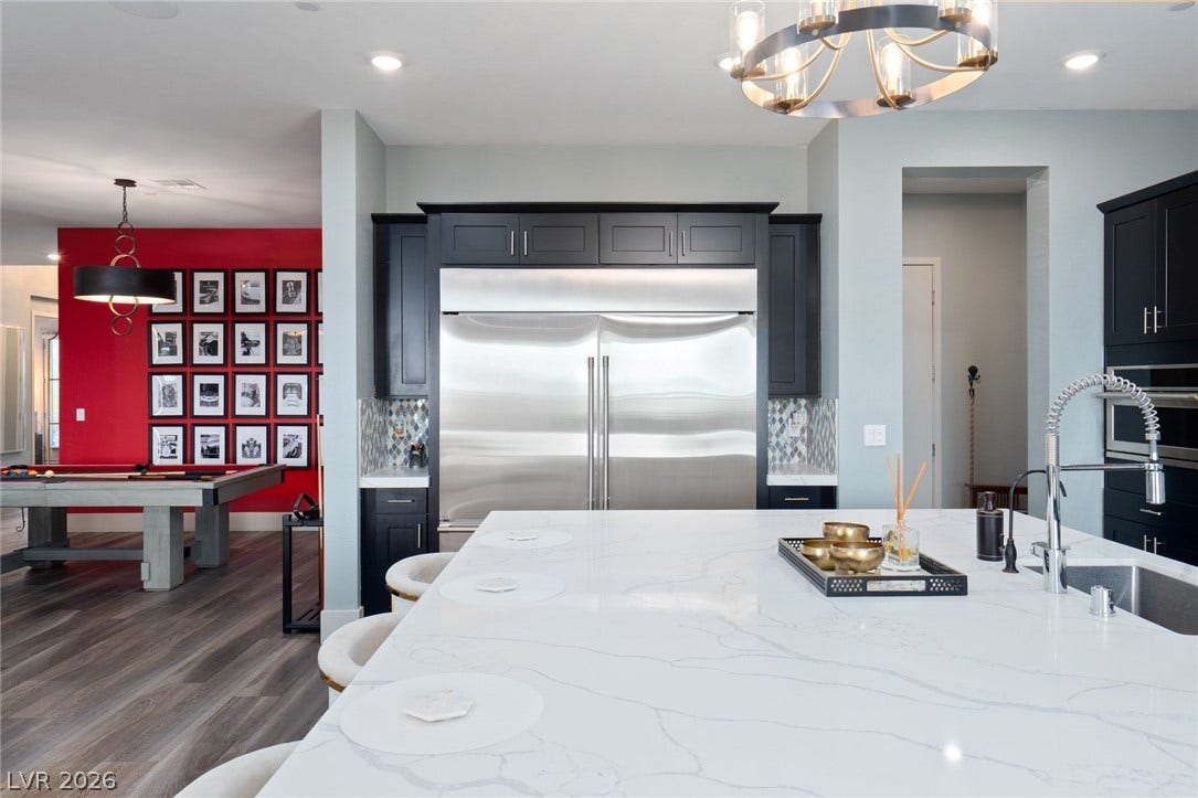 Gleaming stone countertops and dark cabinetry define this open culinary space flowing into adjacent living areas.