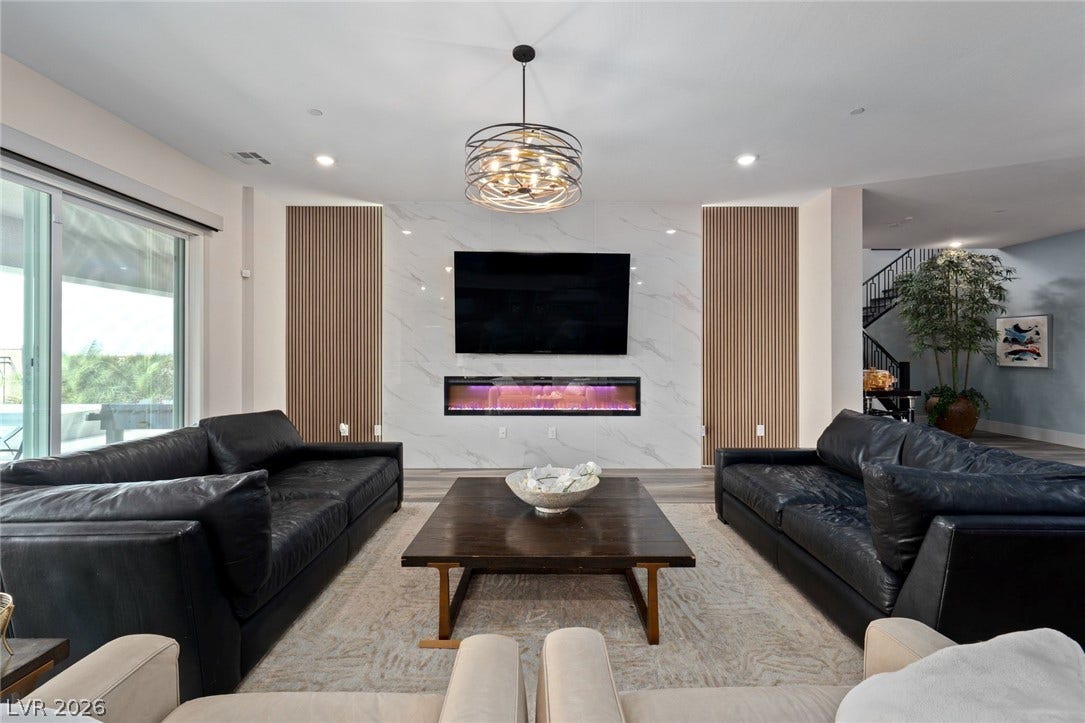 A modern fireplace is set into a marble accent wall alongside recessed lighting and sliding doors.