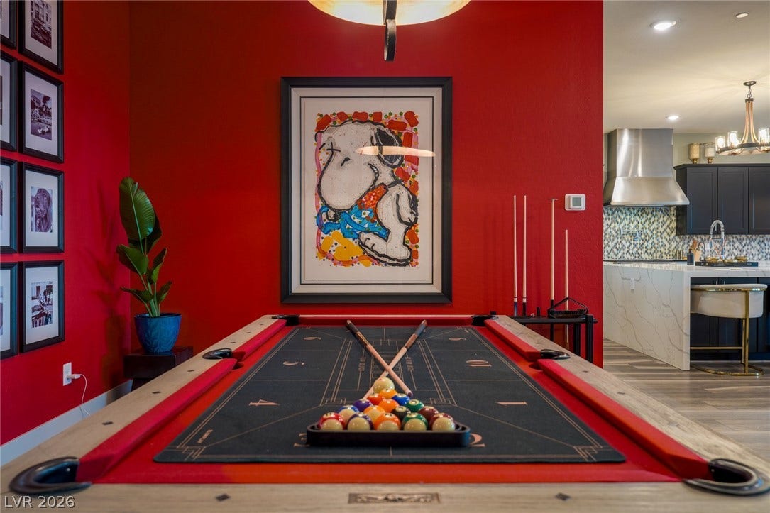 A spacious game area transitions seamlessly into a modern open kitchen with hardwood flooring.