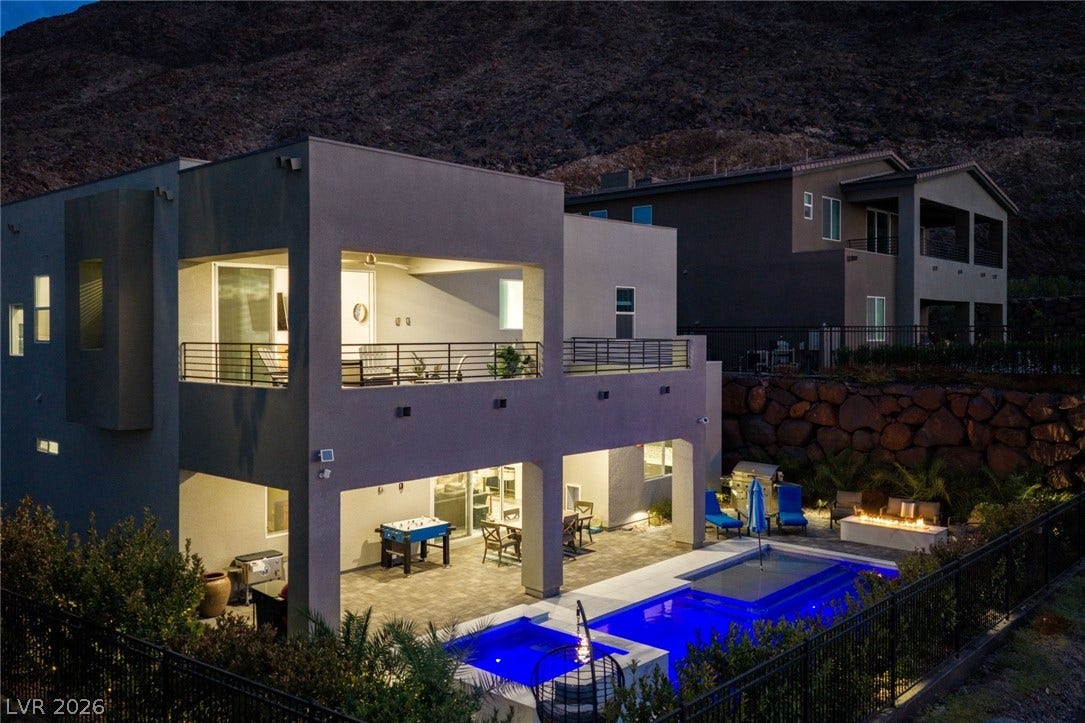 A modern exterior showcases a covered patio, upper balcony, and integrated pool under desert hills.