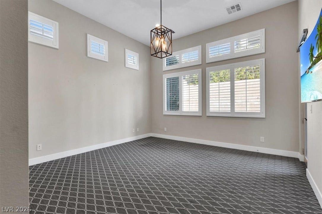 First floor Primary Bedroom Suite featuring premium plush carpet and a chandelier. With separate entry to the pool and yard.