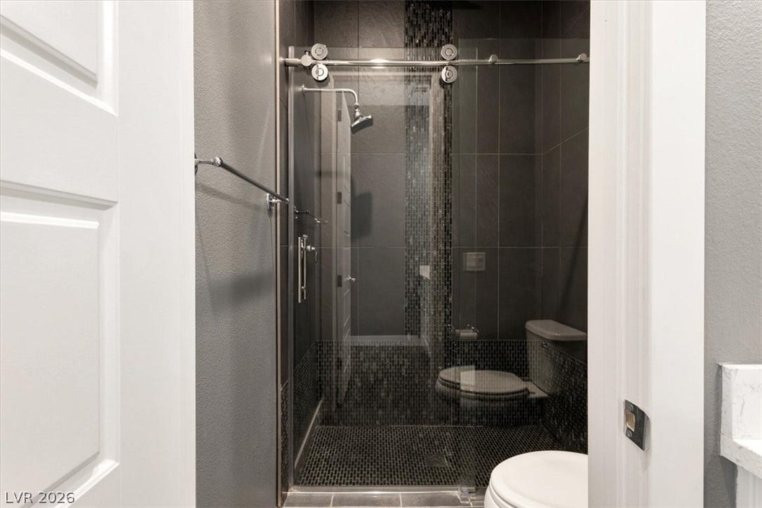 Bathroom with an upgraded glass enclosed shower, premium tile surrounds and a textured wall