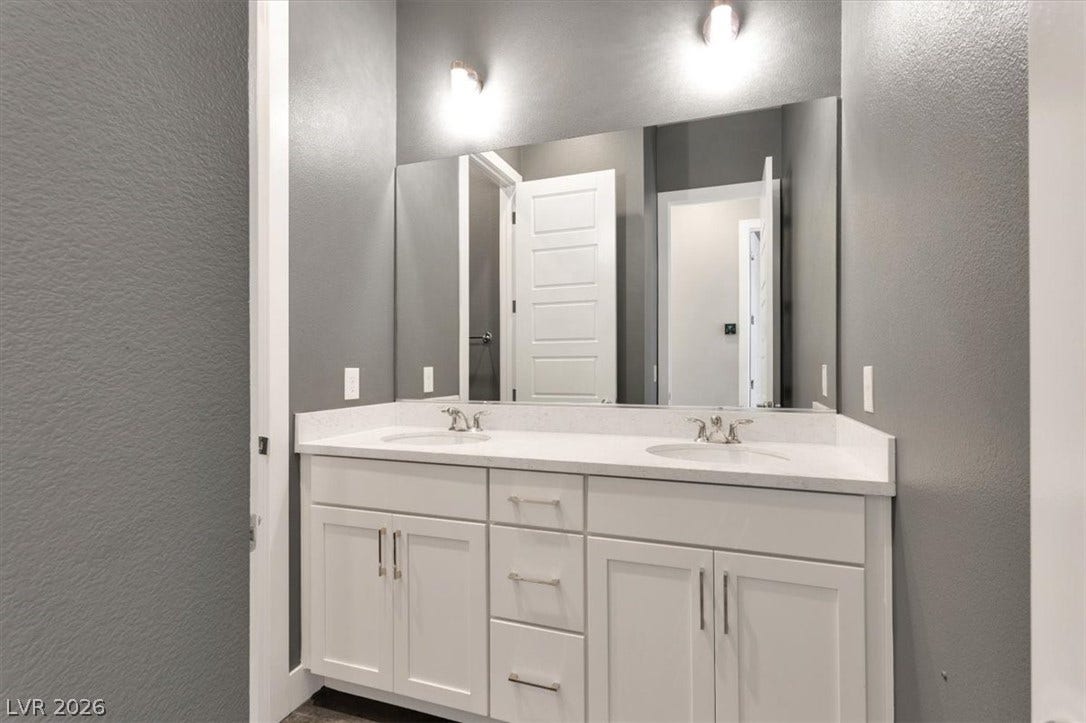Bathroom featuring a textured wall and double vanity
