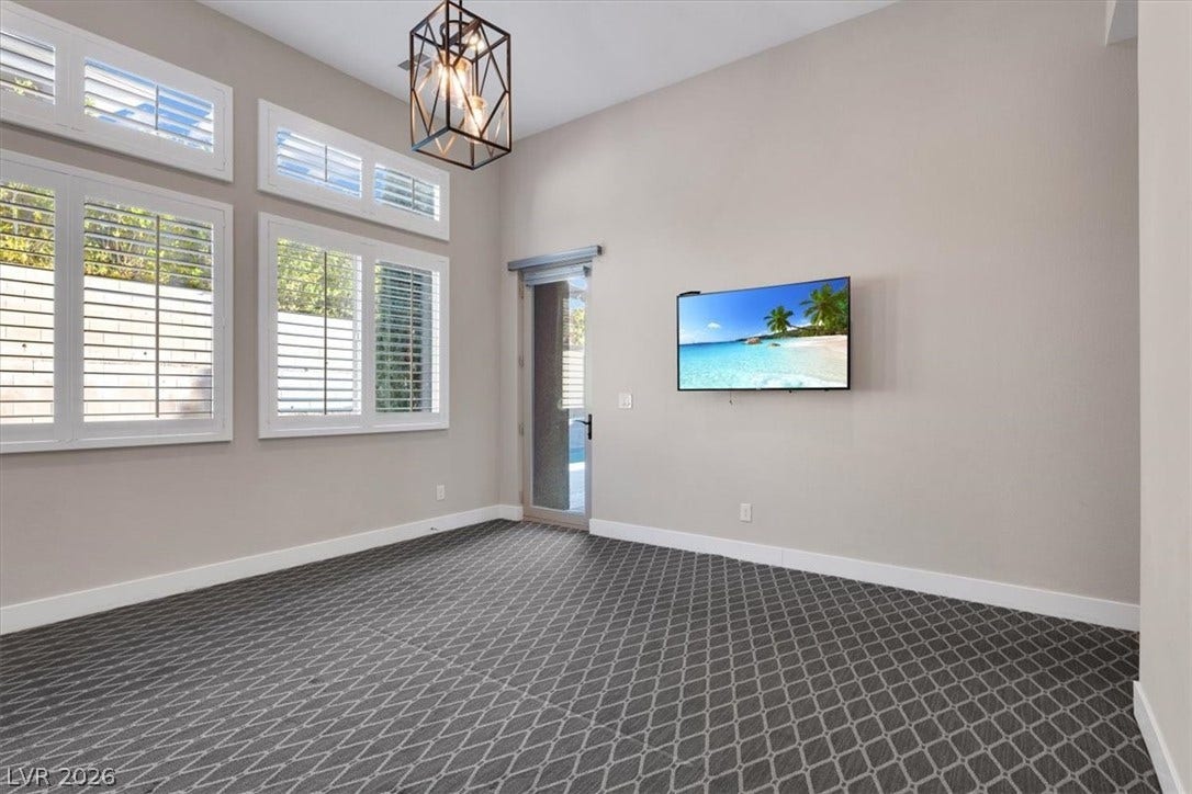 First floor Primary Bedroom Suite featuring premium plush carpet and a chandelier. With separate entry to the pool and yard.
