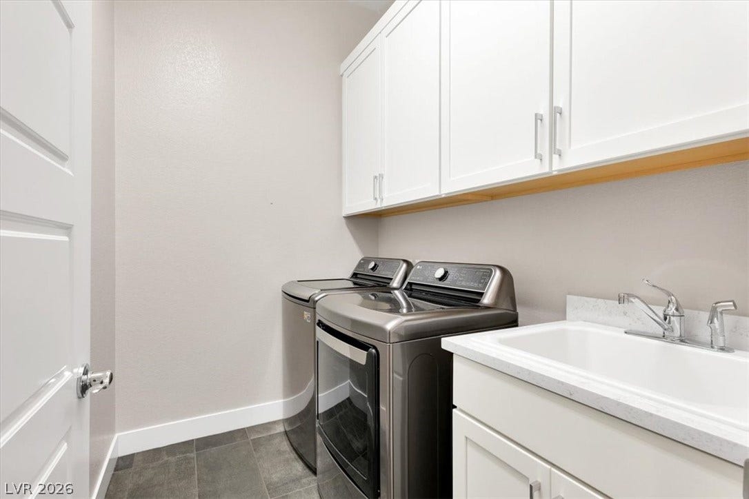 First floor laundry room featuring LG washer and dryer, with cabinets and sink workspace
