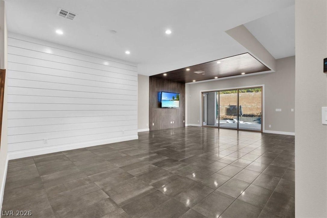 Dining area off of formal entry with wood walls, recessed lighting, and dark tile patterned floors. Open plan living at its finest.