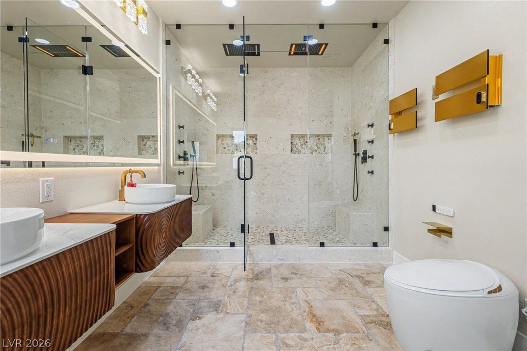 Gleaming stone tile flooring and a massive glass-enclosed walk-in shower elevate this contemporary bathroom.