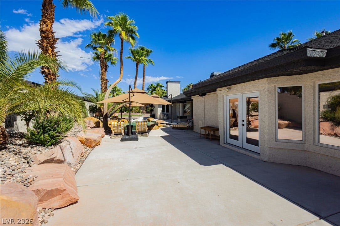 French doors open directly onto a spacious concrete patio flanked by desert landscaping.