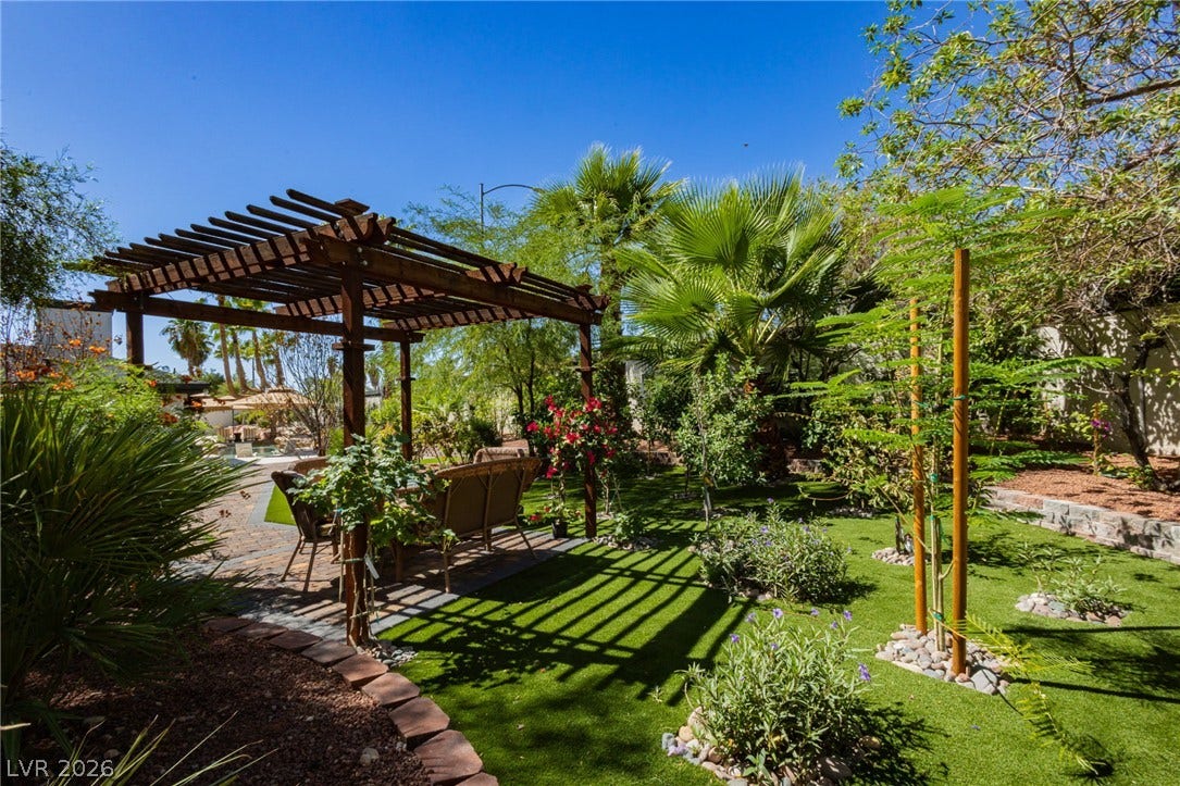 Lush landscaping and a wooden pergola create a tranquil outdoor retreat.