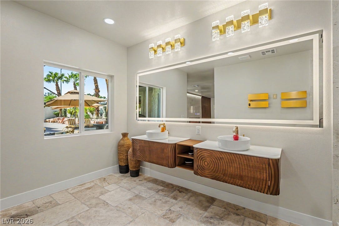 Textured stone flooring pairs beautifully with the floating double vanity and backlit mirror.