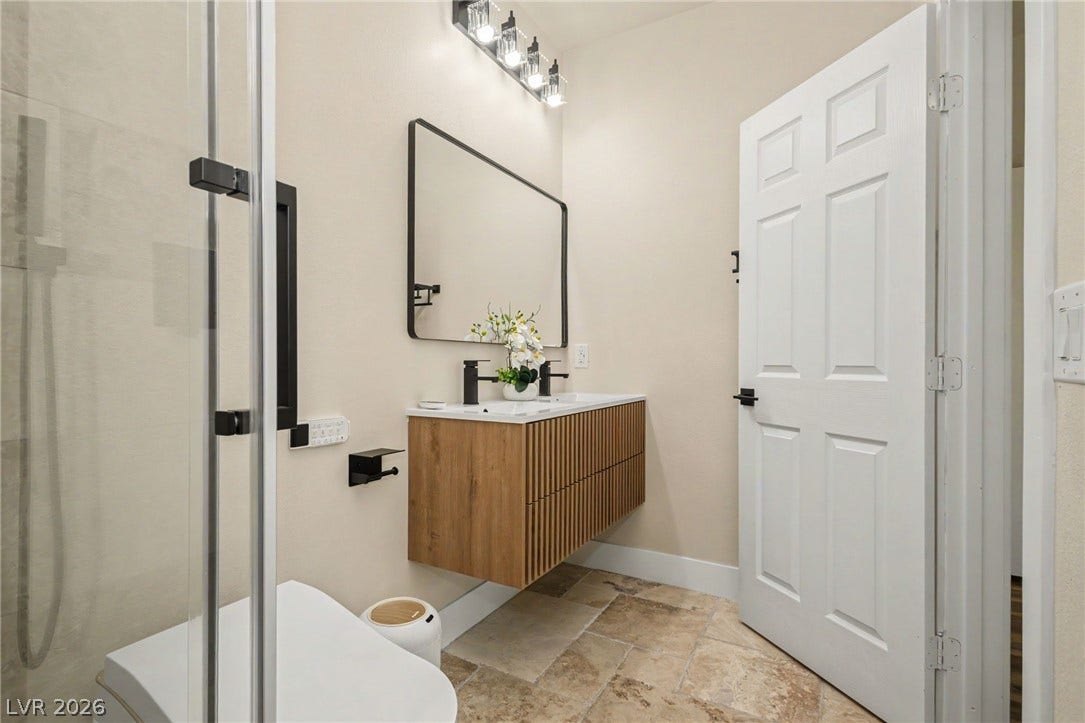 A floating wood vanity pairs with textured stone tile flooring in this modern bathroom.