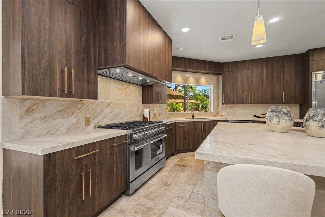 Rich wood cabinetry contrasts beautifully with thick stone countertops in this modern gourmet kitchen.