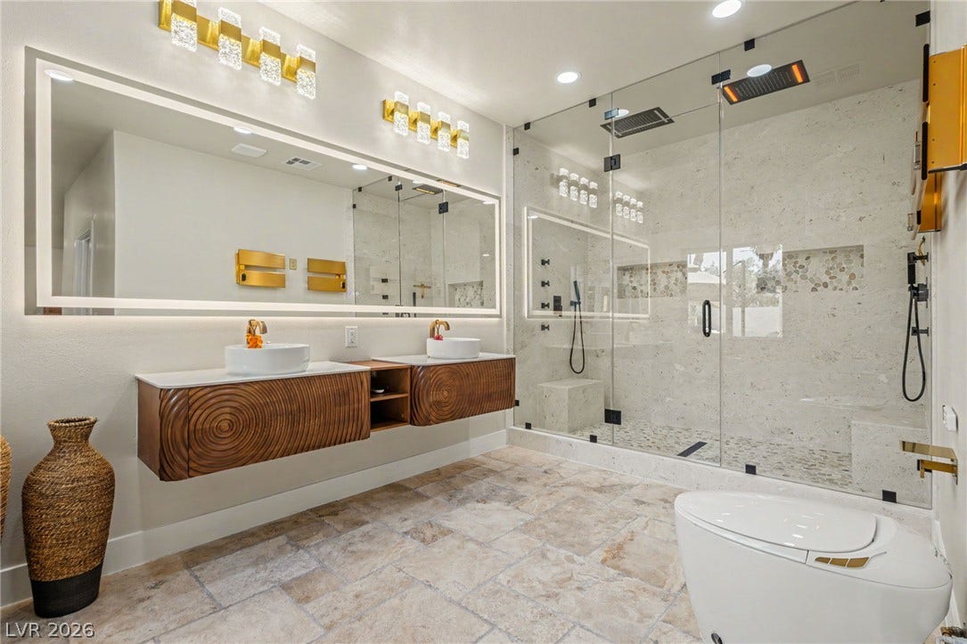 Stone tile floors and a glass walk-in shower define this contemporary master bathroom.