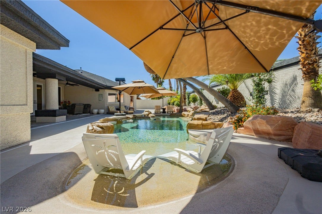 An inviting backyard oasis features a rock-lined swimming pool paired with a spacious patio.