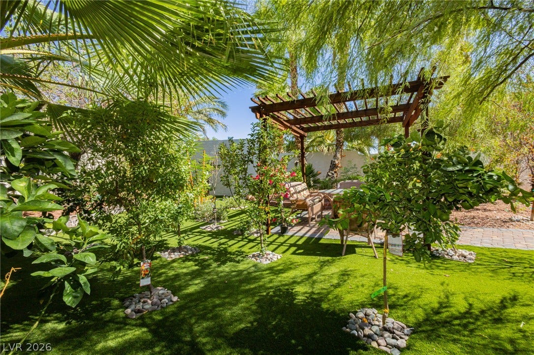 Lush plantings and a classic wooden pergola frame this serene outdoor seating area.