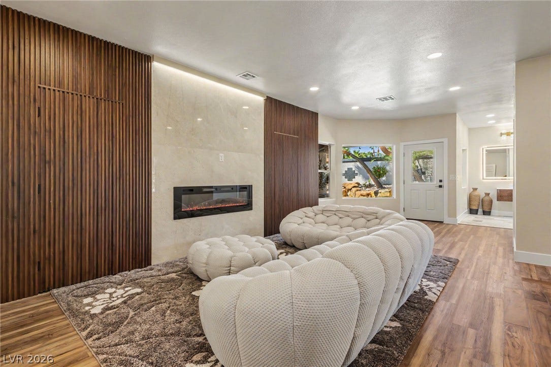 Rich wood paneling flank a modern fireplace in this open living space with hardwood floors.