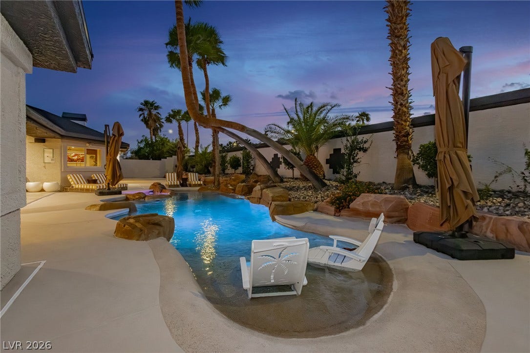 Lush palm trees and natural stone accents frame a serene pool under the twilight sky.