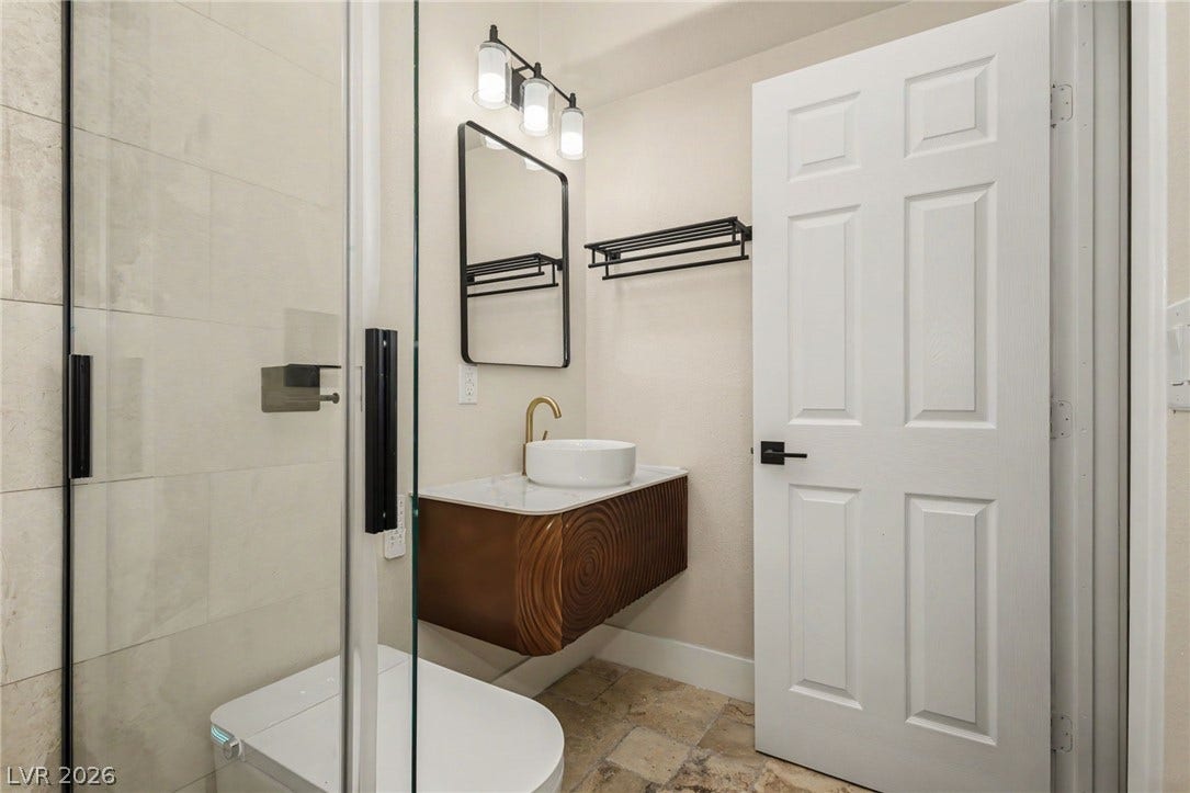 Modern stone tile flooring complements the floating vanity and sleek glass-enclosed shower.