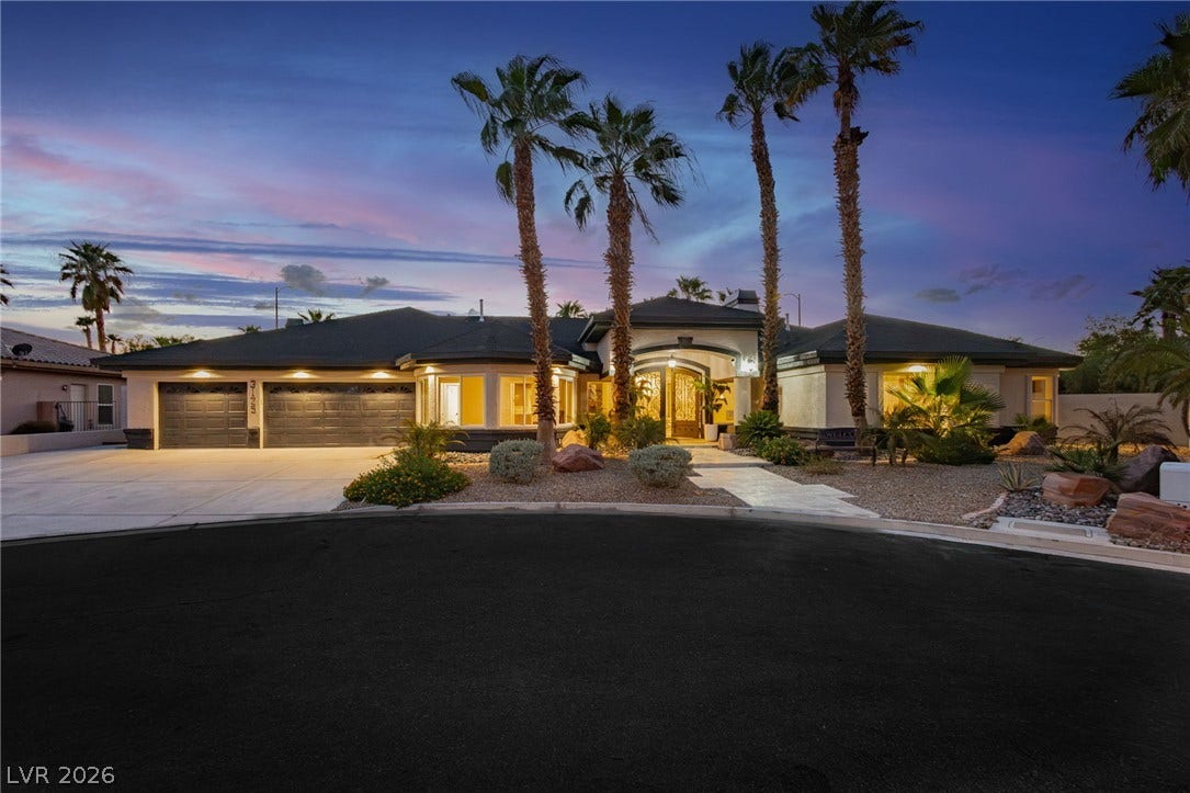 Towering palm trees frame the grand entrance and expansive driveway of this elegant single-story residence.