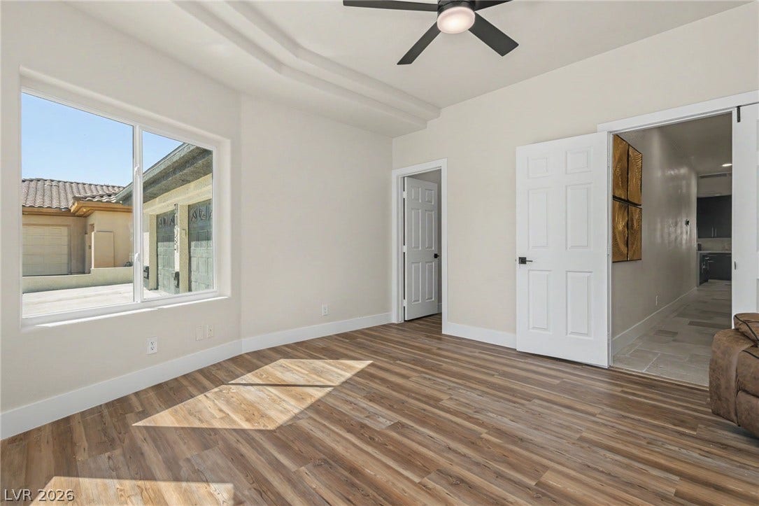Warm wood flooring and a recessed tray ceiling define this inviting room filled with natural light.