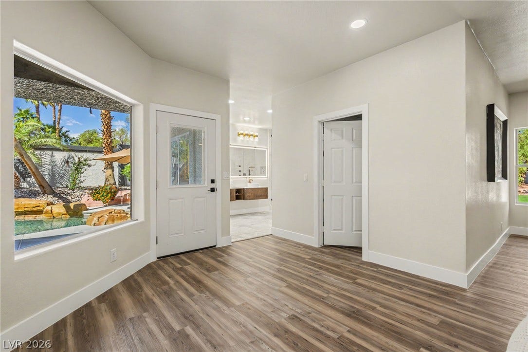 Rich wood-look flooring and tall windows create a bright, inviting entryway.