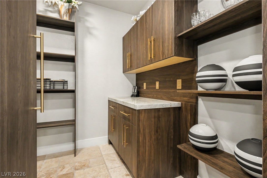 Rich wood cabinetry paired with marble countertops highlights this functional butler pantry area.