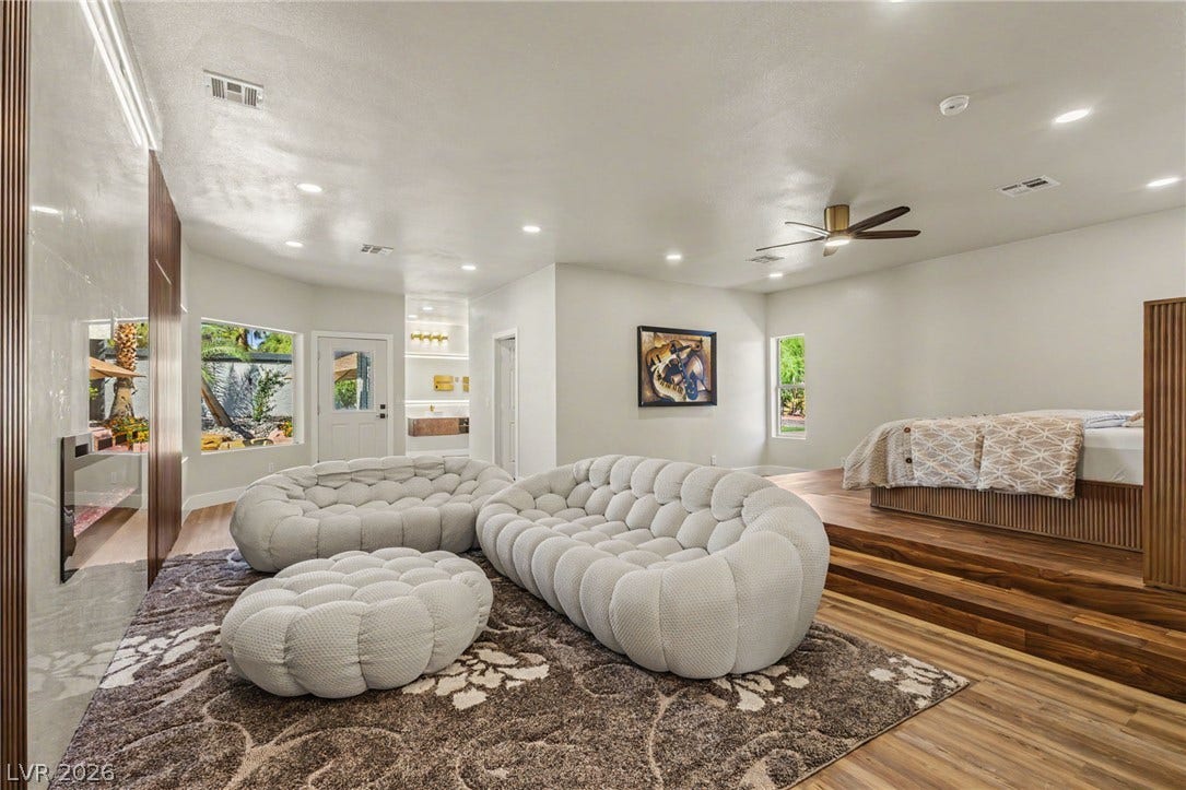 Rich wood steps elevate the bed platform alongside a sleek built-in fireplace.