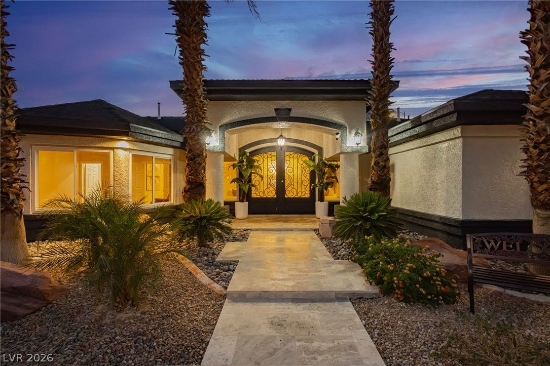 An inviting stone pathway leads to double entry doors under a grand archway.