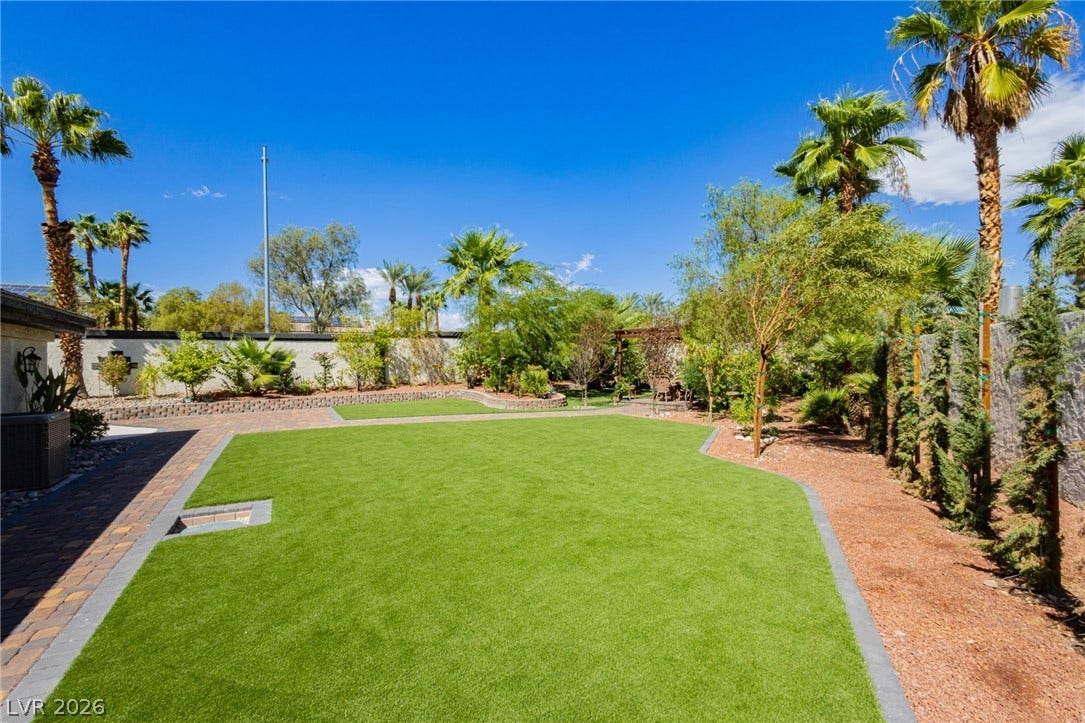 Manicured green lawn borders brick paving under a clear blue sky.